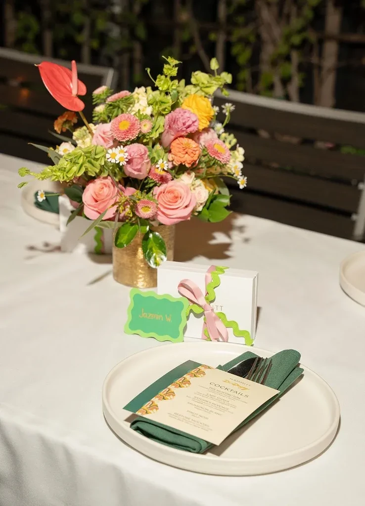 Outdoor table setting with a vibrant floral centerpiece and cocktail menu.