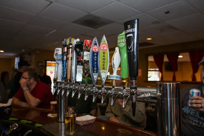 Eleven distinct beer taps lined up behind a bar.