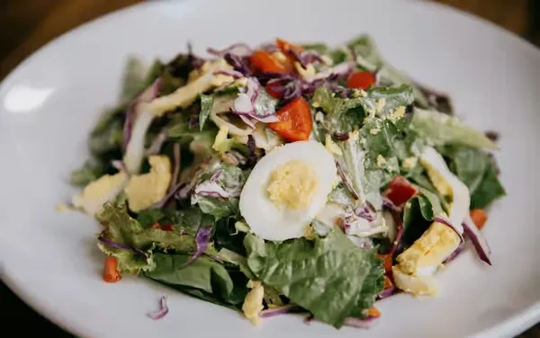 Salad with mixed greens, tomatoes, eggs, and creamy dressing.
