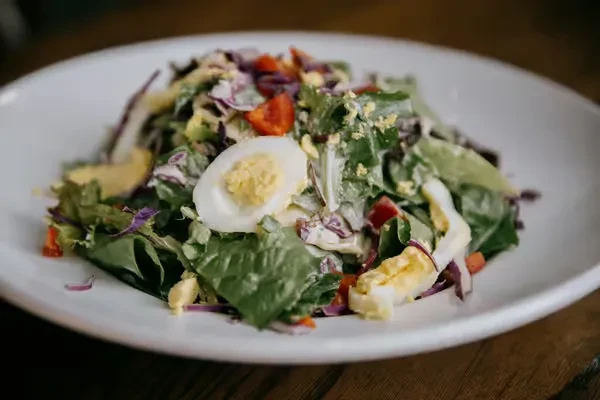 Fresh salad with hard-boiled eggs, red cabbage, and tomatoes.