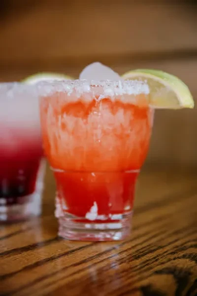 Two colorful, icy drinks in glasses on a wooden surface.