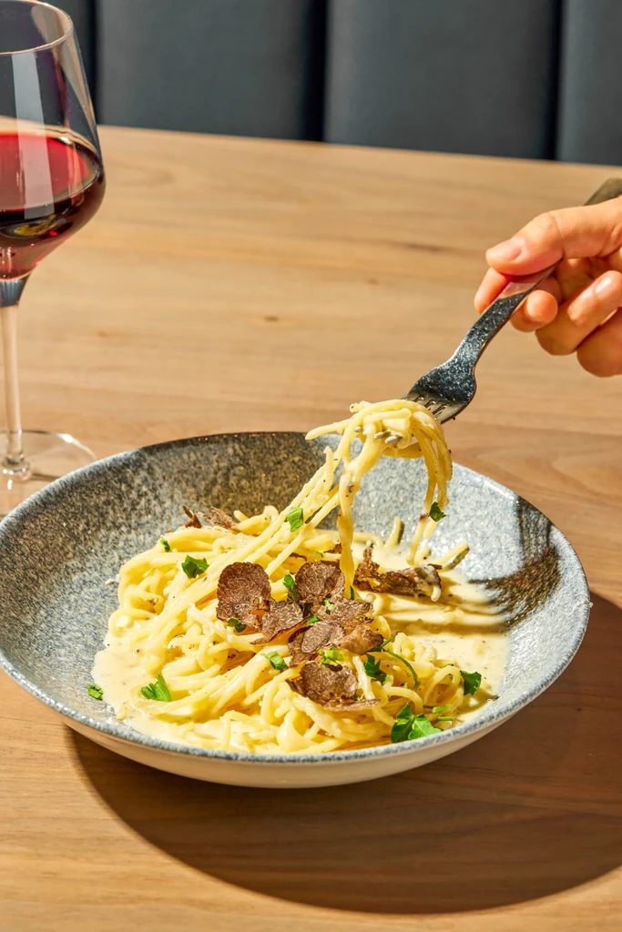 Spaghetti with truffle slices, creamy sauce, and herbs.