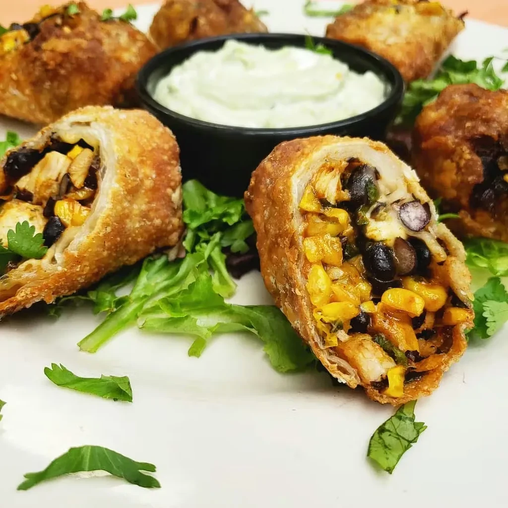 Crispy, golden-brown appetizers cut in half, with a creamy green dipping sauce.