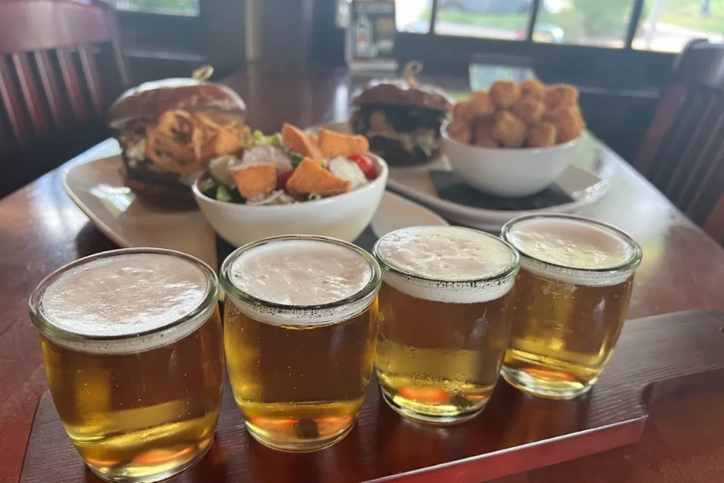 A casual restaurant table with a beer flight, burgers, and salad.