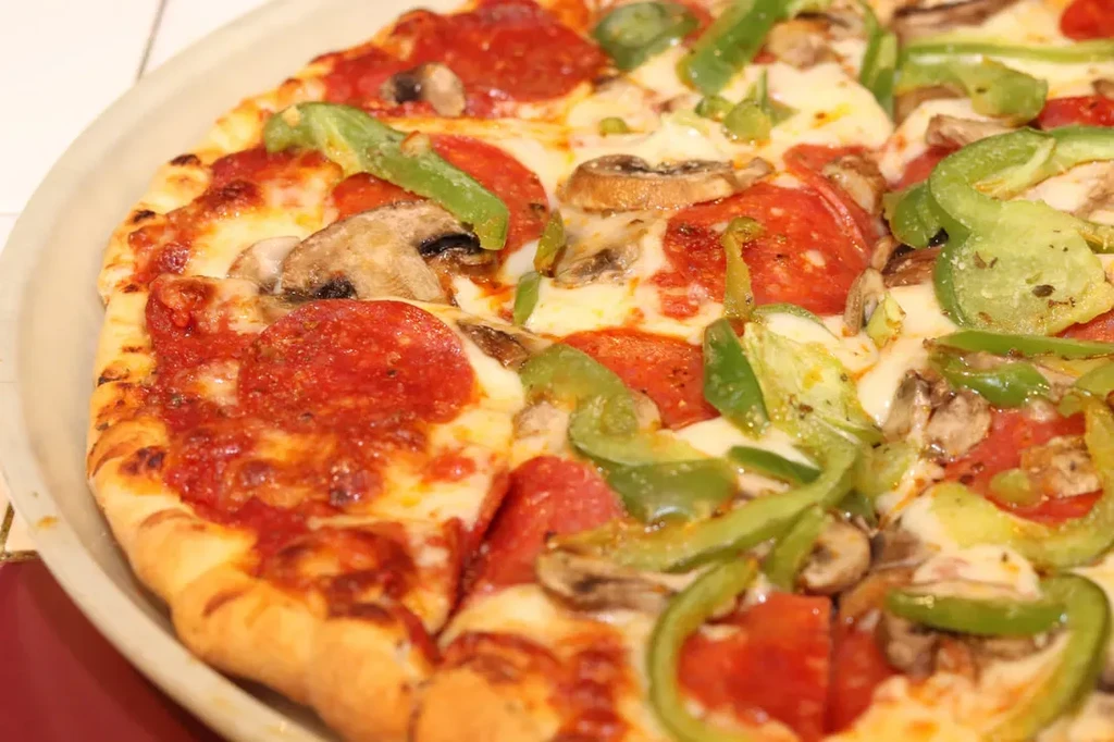 Close-up of a pizza with pepperoni, mushrooms, and green peppers.