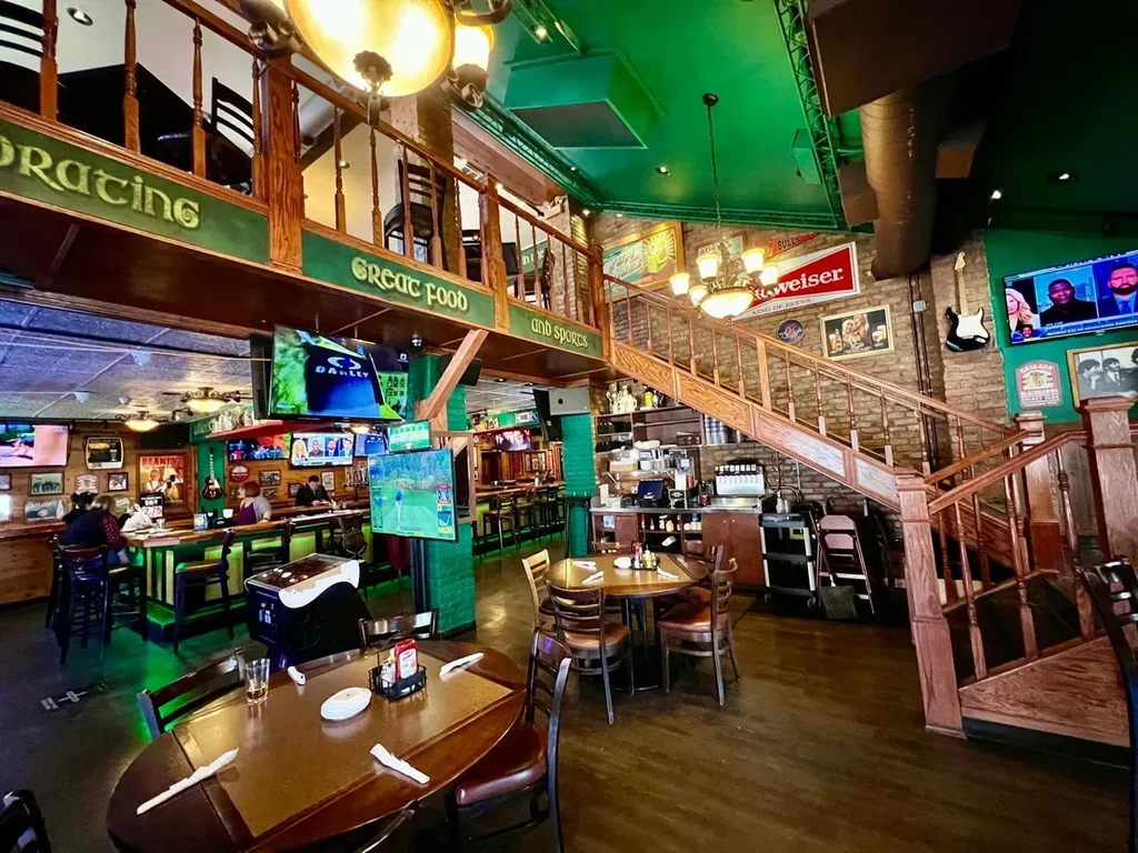 Interior of a lively, multi-level restaurant and bar with TVs.