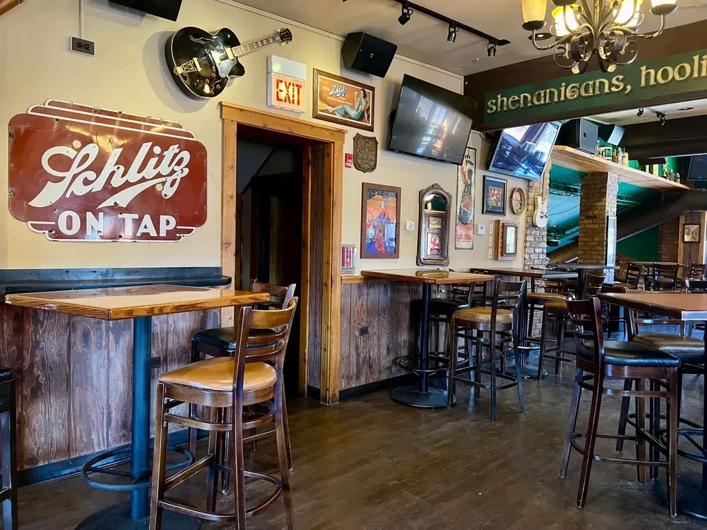 Interior of a bar with high-top tables and Schlitz sign.