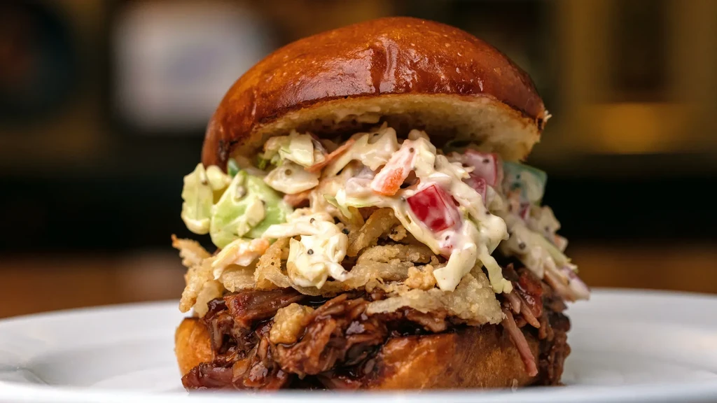 Gourmet pulled pork sandwich on brioche with coleslaw and crispy onions.