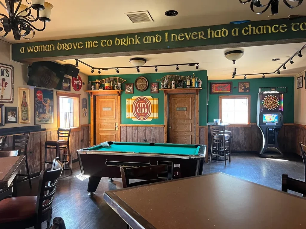 Rustic bar interior with a pool table and dark wood decor.