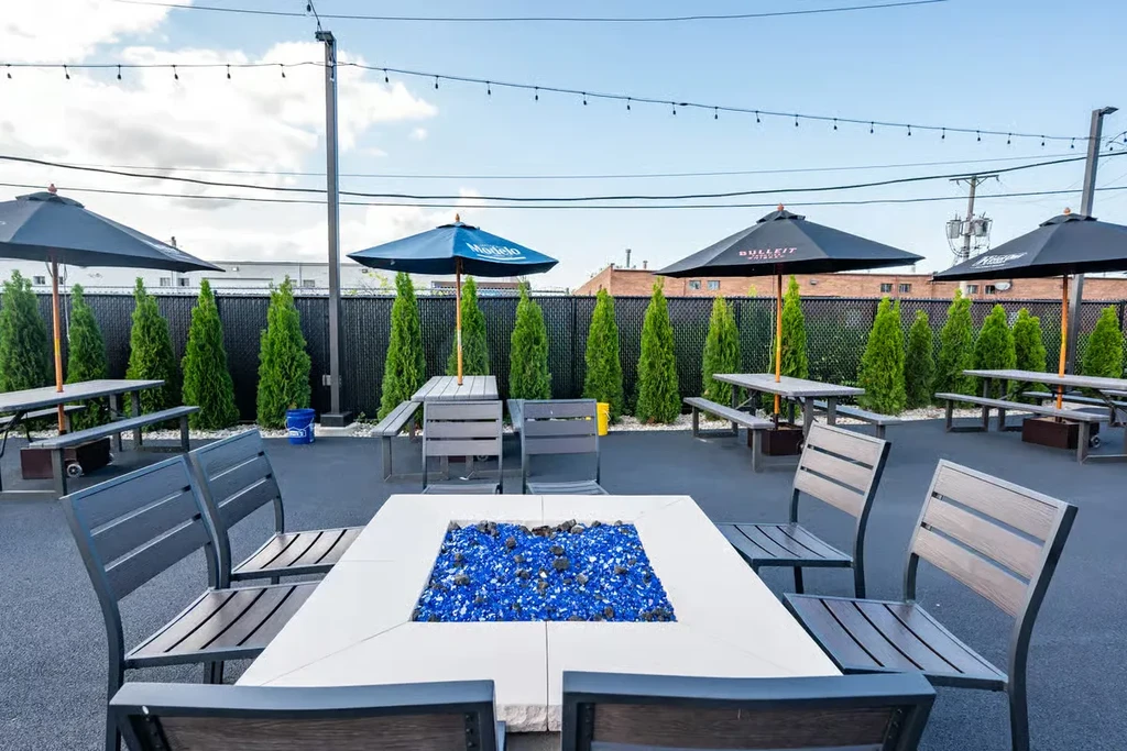 Outdoor patio with a fire pit table, picnic tables, and umbrellas.