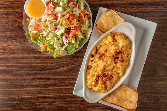 Salad in glass bowl, macaroni and cheese in white dish.