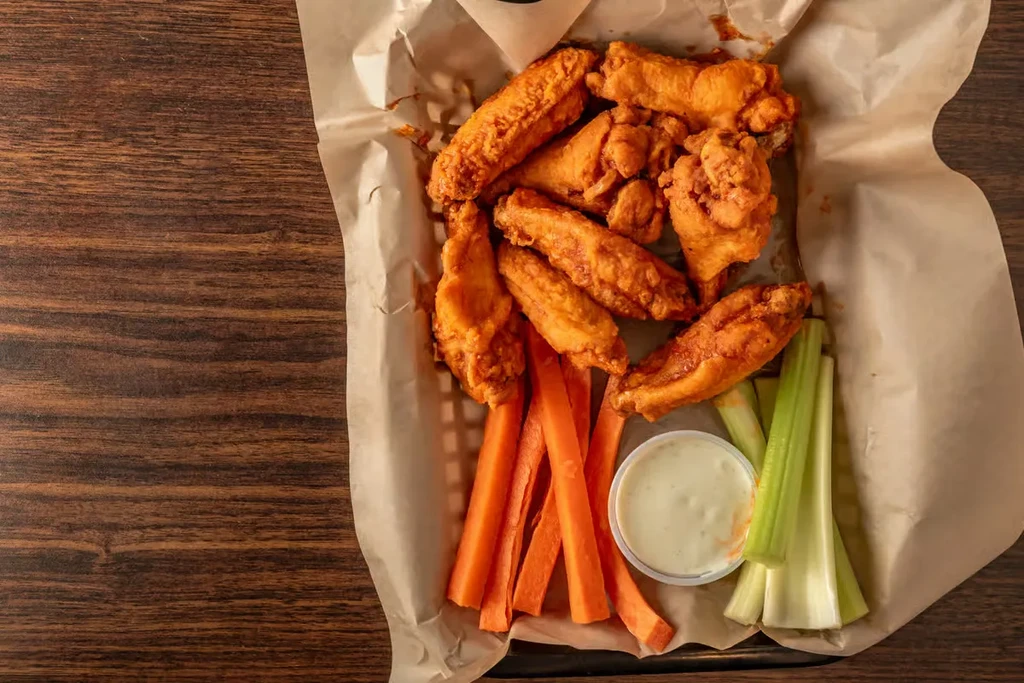 Fried chicken wings, carrot, and celery sticks with dipping sauce.