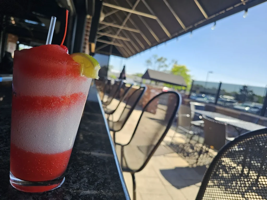 Striped red and white frozen drink with cherry and lime.