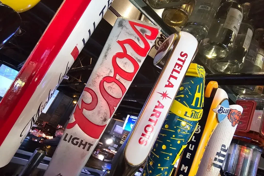 Close-up of several beer tap handles with visible brand names.