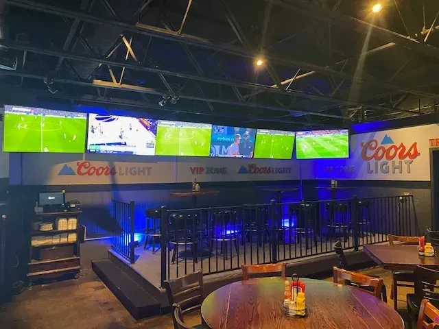 Sports bar with multiple TVs, Coors Light branding, and seating.