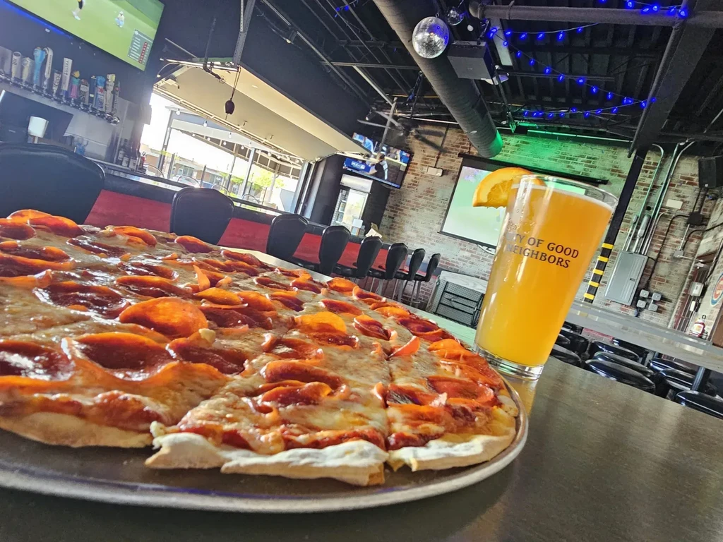 Pepperoni pizza, beer, and restaurant interior with exposed brick walls.
