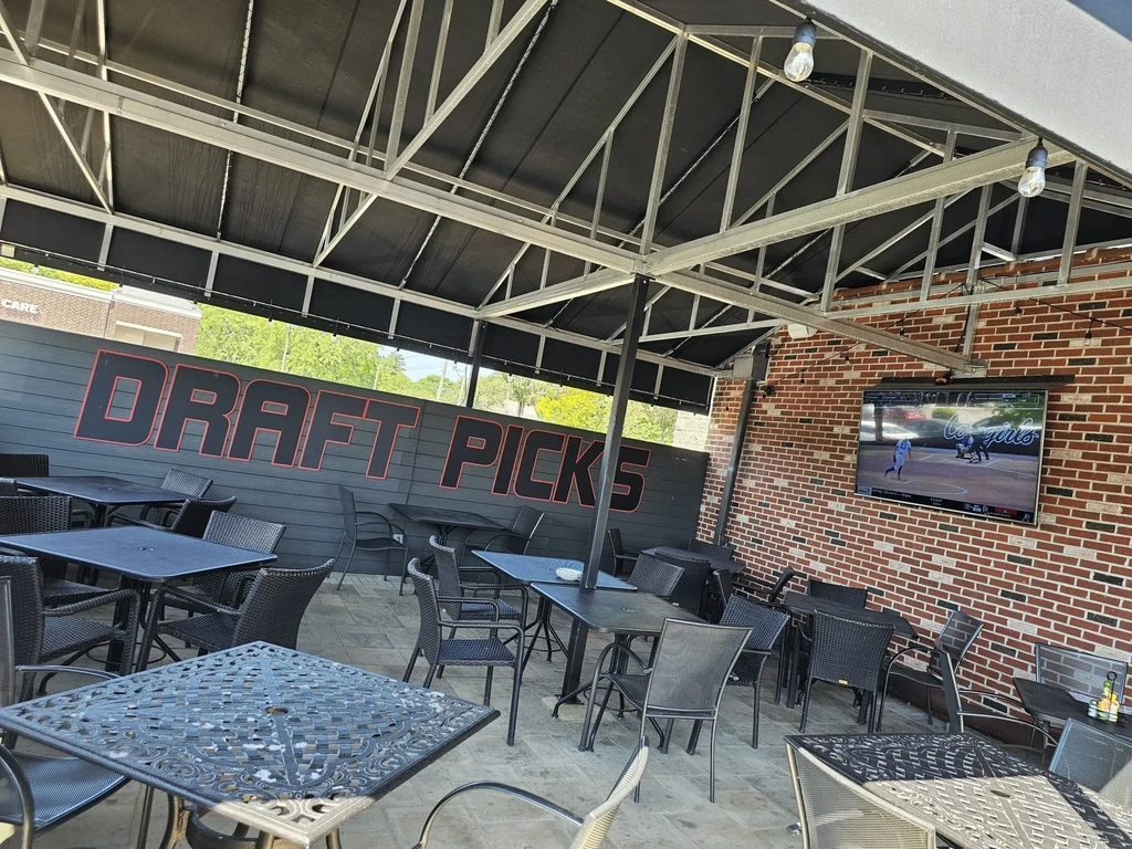 Outdoor patio with dark tables, chairs, awning, and a TV.