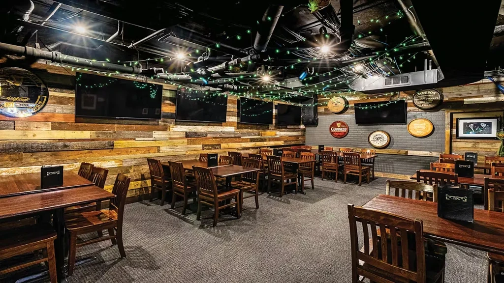 Empty rustic-industrial pub with barrel signs, wood walls, and festive green lights.
