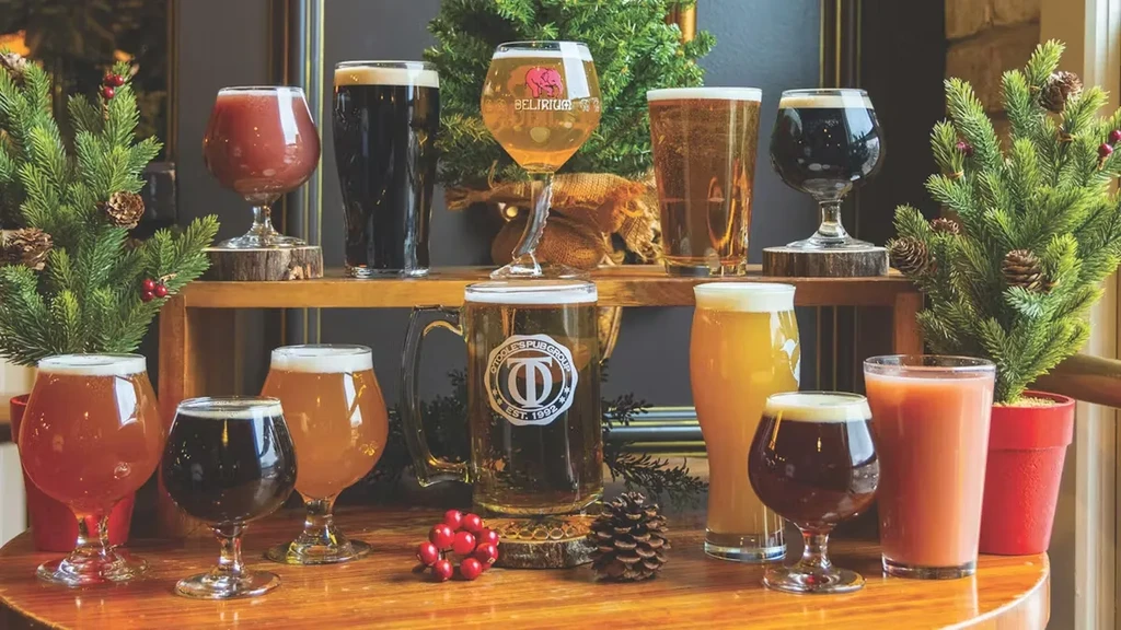 Twelve diverse beers and drinks on a festive pub table.
