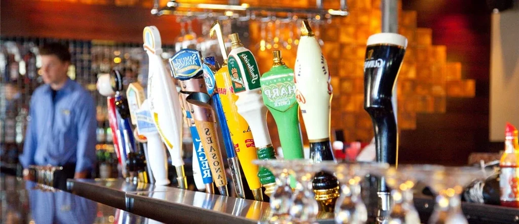 Beer taps, including Guinness and Samuel Adams, at a bar counter.