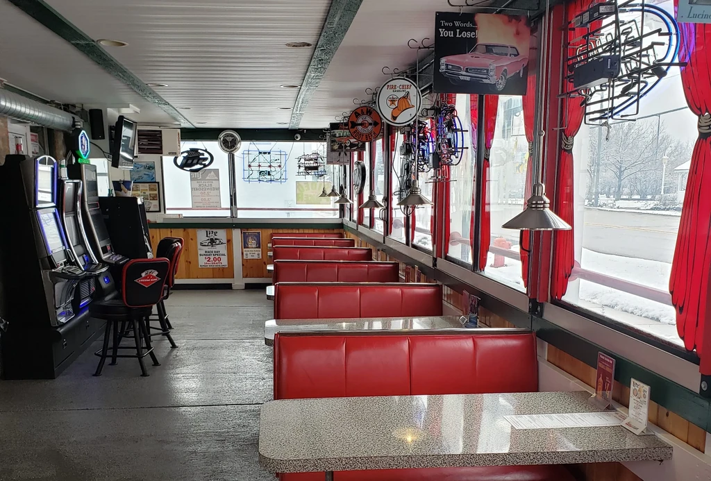 Empty retro diner interior with red booths and a snowy street view.