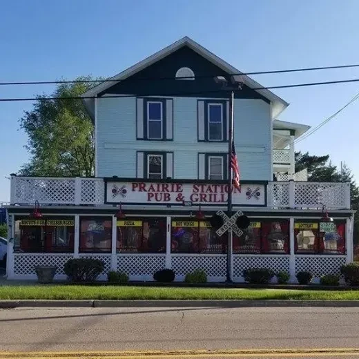 Two-story Prairie Station Pub & Grill with a railroad crossing sign.