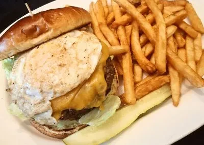 Overhead plate with egg-cheese burger, fries, and a pickle.