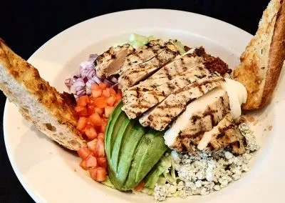 Grilled chicken salad with avocado, tomato, blue cheese, lettuce, toast.