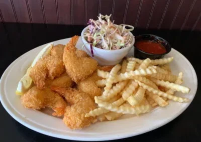Fried shrimp and fries platter with coleslaw and dipping sauce.