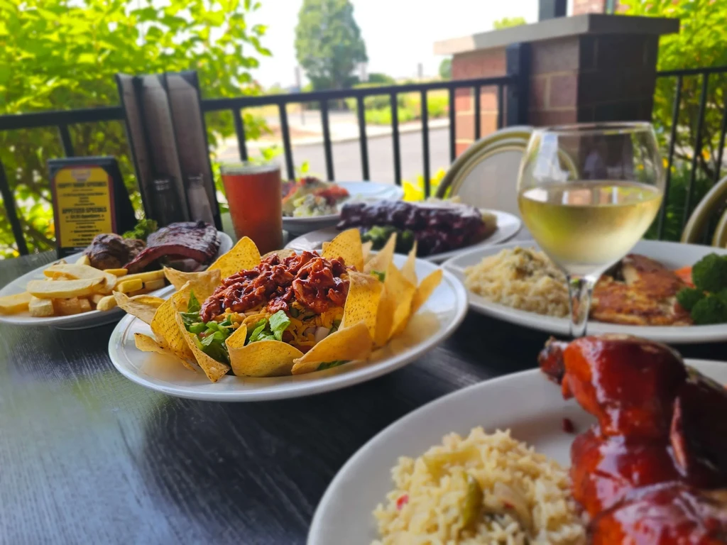 Vibrant outdoor spread of nachos, ribs, wine, and beer on a table.