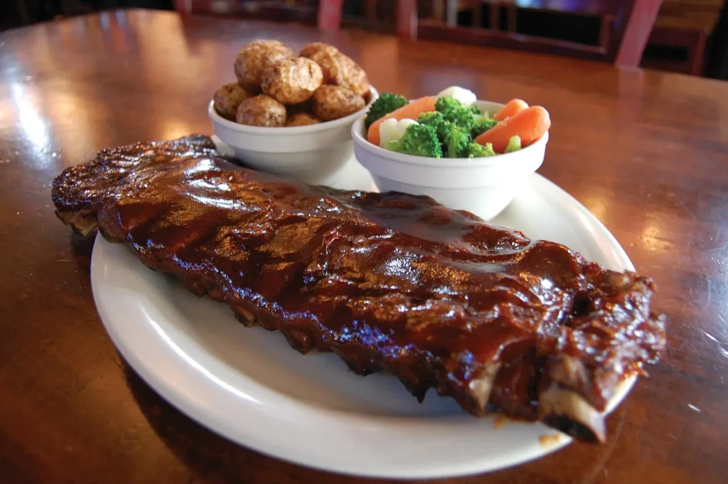 BBQ ribs, roasted potatoes, and steamed vegetables on a plate.