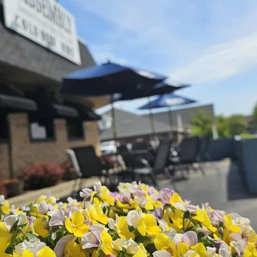 Yellow and purple pansies foreground, blurred outdoor restaurant patio.