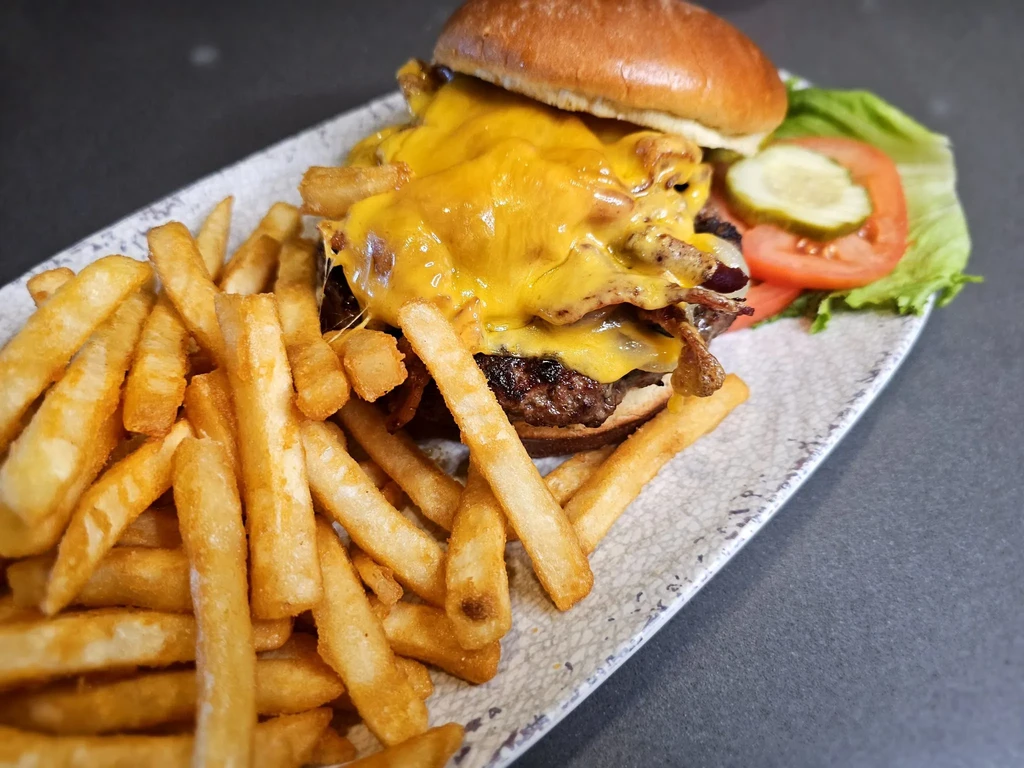 A cheeseburger with melted cheese, bacon, and thick-cut french fries.