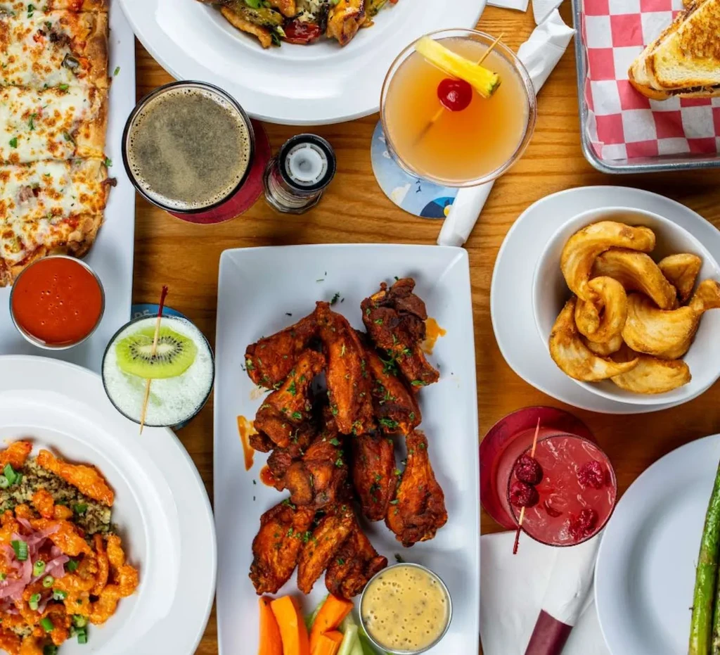 Overhead view of a wooden table with various restaurant dishes and drinks.