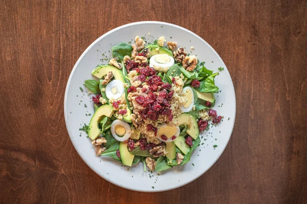 Overhead salad with spinach, avocado, quail eggs, quinoa, cranberries, walnuts.