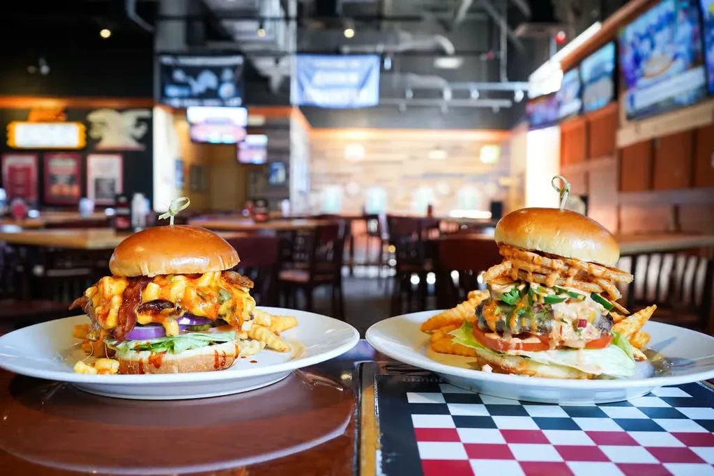 Two gourmet burgers with waffle fries in a casual restaurant.