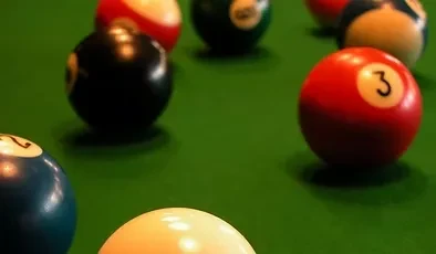 Close-up of scattered colorful pool balls on green felt.