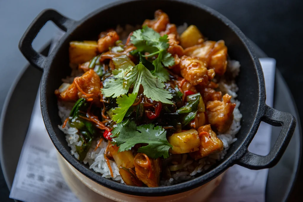 Top-down view of chicken, pineapple, and rice in a cast-iron pot.