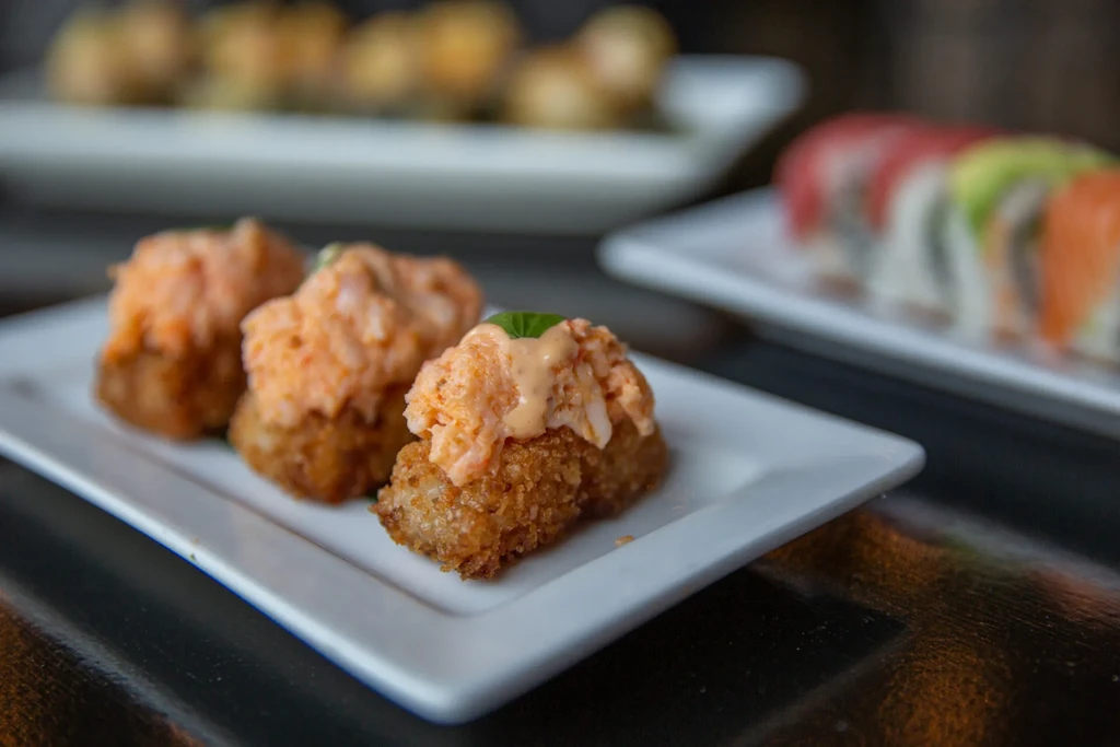 Three golden-brown croquettes with orange sauce and green garnish.