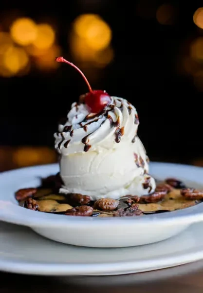 Vanilla ice cream, whipped cream, cherry on warm dessert with pecans.