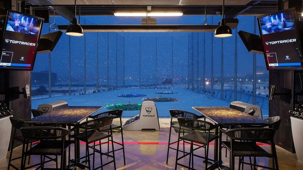 Topgolf bay looking out at a snowy driving range with glowing targets.