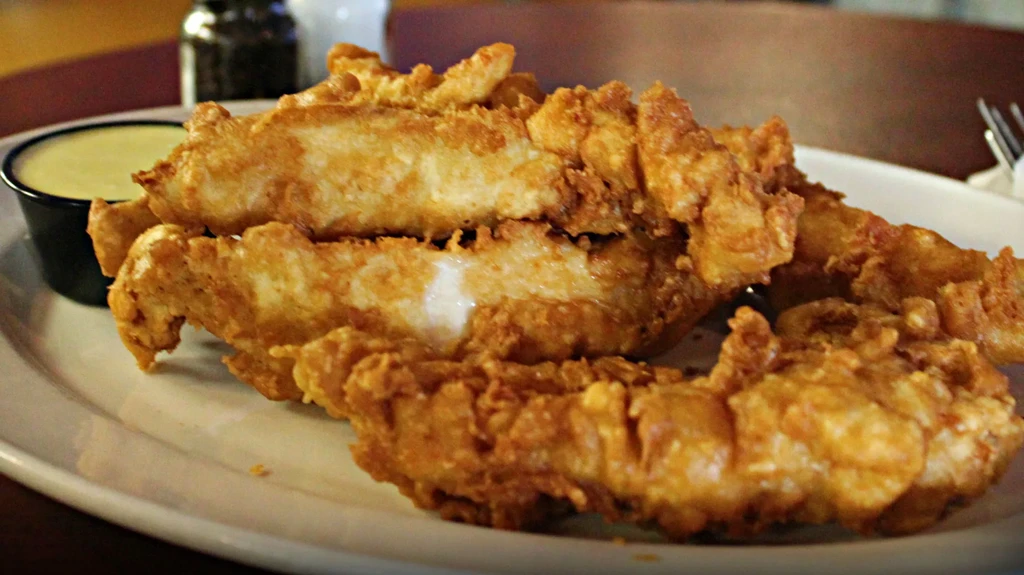 White plate with crispy golden fried food and dipping sauce.
