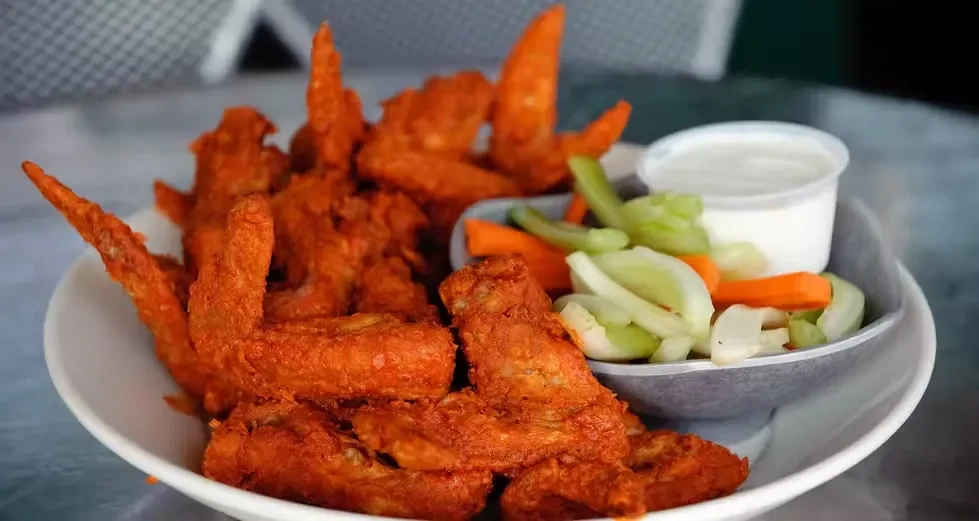 Plate of buffalo wings, celery, carrots, and white dipping sauce.
