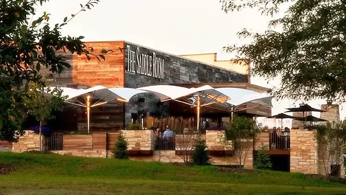 The Saddle Room restaurant, modern rustic exterior, with people on patio.