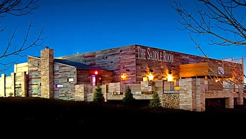 The Saddle Room's rustic wood and stone exterior, prominent chimney.