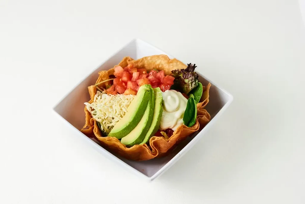 Close-up of a colorful taco salad in a crispy tortilla bowl.