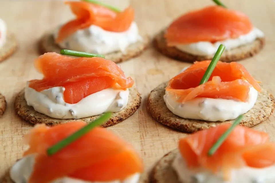 Smoked salmon canapés with cream cheese and chives on a wooden board.