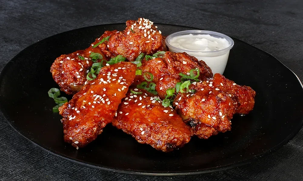 Glazed chicken wings with sesame seeds, green onions, and creamy dipping sauce.