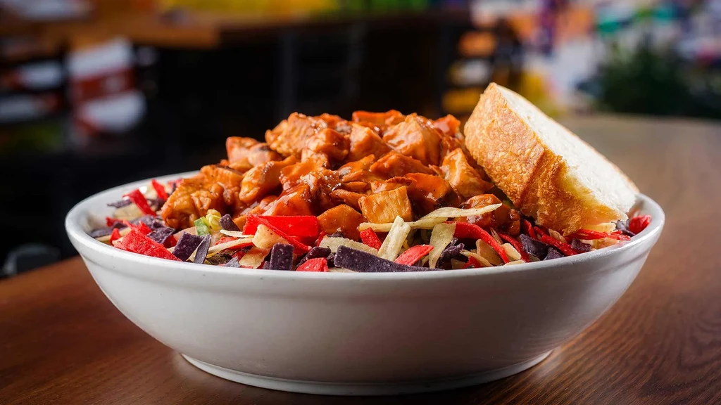 Chicken in reddish-orange sauce over colorful tortilla strips.