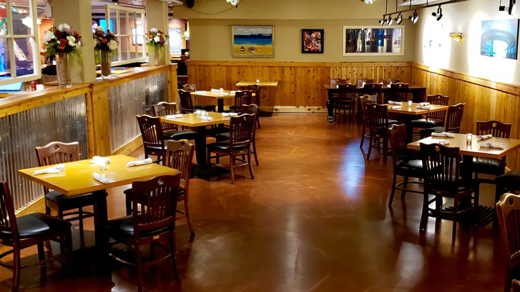 Restaurant interior with wooden walls, metal accents, and set tables.